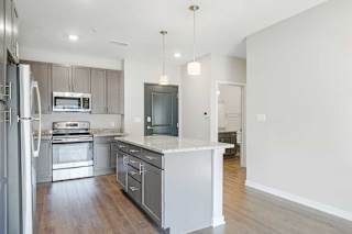 an open-concept kitchen with a large island next to a hallway