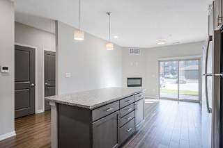 a kitchen with an island next to an open living room and a doorway to the hall