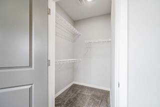 a walk-in closet for the second bedroom with built-in shelves