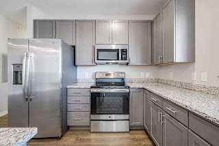 a kitchen with stainless steel appliances, grey cabinets, and granite counter tops