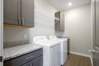 a large laundry room with a full-sized washer and dryer with over head shelving and cabinet storage