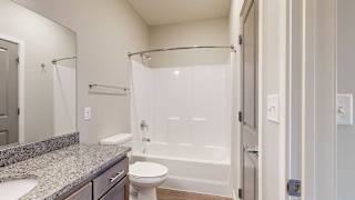a bathroom with a tub shower and a granite counter top vanity sink