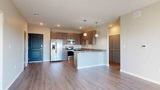 a kitchen with a peninsula, stainless steel appliances, and grey cabinets extending into a living room