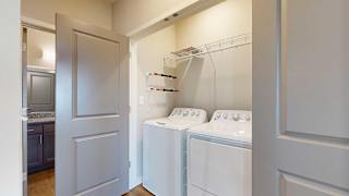 a laundry room with a full-sized side-by-side washer and dryer and overhead storage