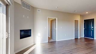 a living room with a fireplace and a door into the primary bedroom