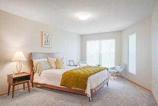 Furnished bedroom with a bed and chairs and a window