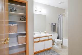 Linen closet next to bathroom with a toilet and a sink and a mirror and shower and tub combo