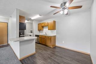 Open apartment dining area with wood-style flooring, a breakfast bar, ceiling fan, and adjoining kitchen with wood cabinetry.