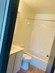 A white toilet sits in a bathroom next to a bathtub.