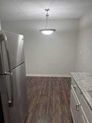 A kitchen with a stainless steel refrigerator and wooden flooring.
