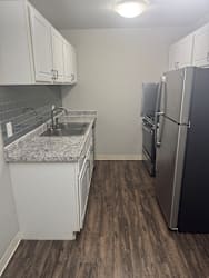A kitchen with a sink, refrigerator, and cabinets.
