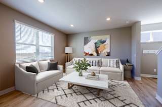 A living room with a white couch, a coffee table, and a painting on the wall.