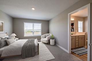 A bedroom with a bed, chair, and window.