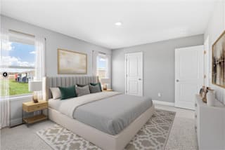 A bedroom with a large bed and a window overlooking a lawn.