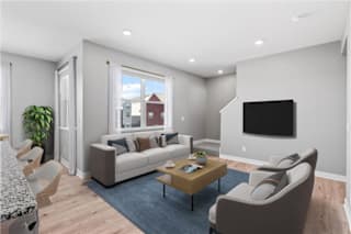 A modern living room with a large couch, a coffee table, and a flat-screen TV.