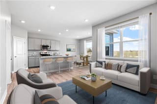 A modern living room with a kitchen area in the background.