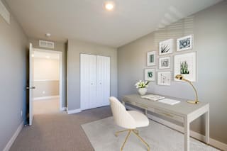 A white chair is in front of a desk with a lamp on it.