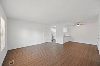 an empty living room with wood flooring and a ceiling fan