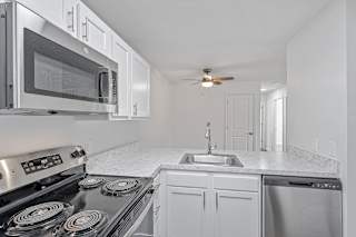 a kitchen with white cabinets and stainless steel appliances and a sink