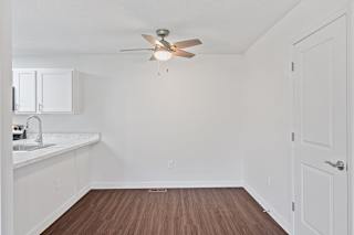 an empty living room with a ceiling fan and a kitchen