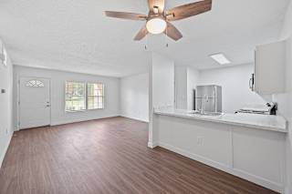 an empty living room and kitchen with a ceiling fan