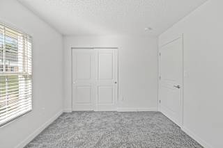 an empty bedroom with white walls and a window