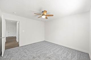 an empty living room with white walls and a ceiling fan