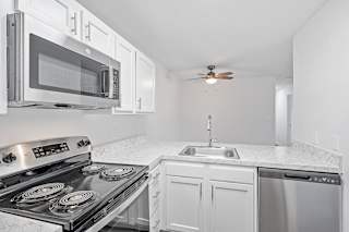 a kitchen with white cabinets and stainless steel appliances and a microwave