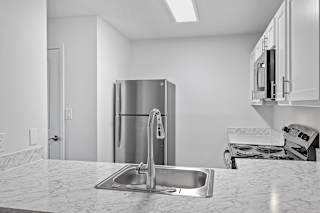 a kitchen with a sink and a stainless steel refrigerator