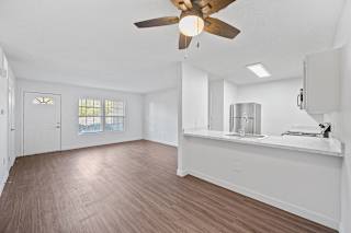 an empty living room and kitchen with a ceiling fan