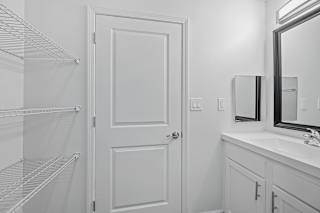 a white bathroom with a shower and a sink and a white door