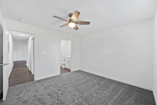 a living room with white walls and a ceiling fan