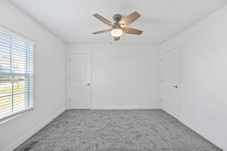 an empty room with a ceiling fan and a window