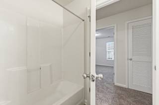 A white bathroom with a tub and a door.