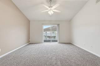 A spacious room with a ceiling fan and carpeted floor.