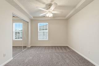 A room with a ceiling fan and carpeted floor.