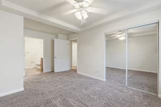 A spacious room with a ceiling fan and carpeted floor.