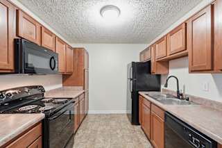 A kitchen with black appliances and brown cabinets.