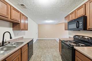 A kitchen with brown cabinets and black appliances.