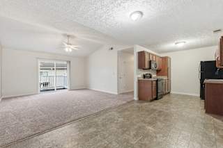 A spacious living room with a kitchenette and a balcony.