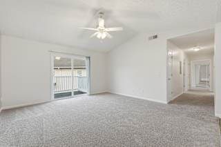 A spacious room with a ceiling fan and carpeted floor.