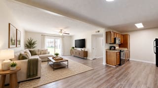 A living room with a couch, a coffee table, a television, and a refrigerator.