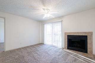 Vacant living room in a Skyler Ridge model unit with a fireplace and ceiling fan.
