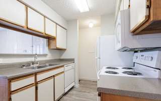 Empty kitchen at Skyler Ridge featuring wood cabinets and white appliances.