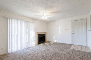 Vacant living room in a Skyler Ridge model unit with a fireplace and ceiling fan.