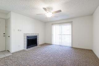 Vacant living room in a Skyler Ridge model unit with a fireplace and ceiling fan.