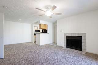 An empty living room and kitchen in a model unit at Skyler Ridge Complex, featuring a ceiling fan and open layout.