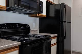 A model unit kitchen at Skyler Ridge Complex with black appliances, a sink, a refrigerator, and a stove.
