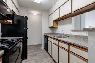 A kitchen in a model unit at Skyler Ridge Complex, featuring black appliances, a sink, a refrigerator, and a stove.