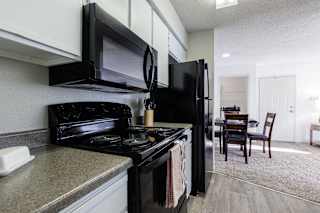 A kitchen in a model unit at Skyler Ridge Complex, featuring black appliances, a sink, a refrigerator, and a stove.